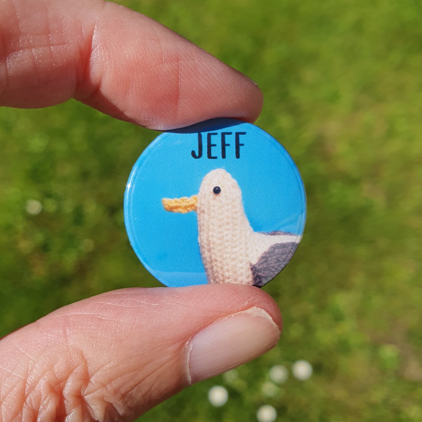 a blue button badge with a knitted seagull on it called Jeff