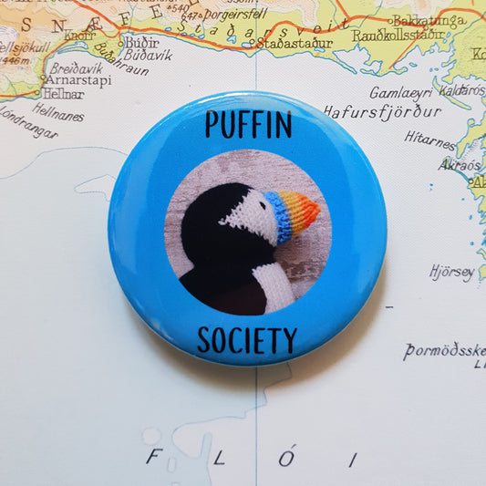 Knitted puffin button badge with a photo of a knitted puffin on it and the text Puffin Society