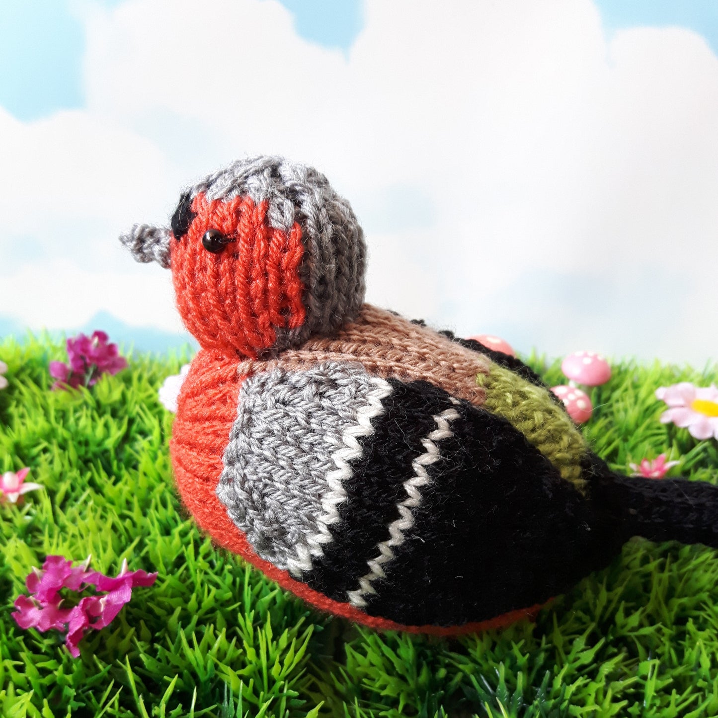 a knitted chaffinch bird sitting on the grass