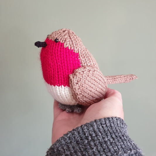 a knitted robin toy being held in a hand