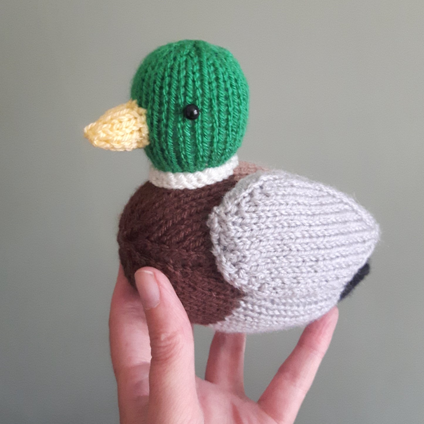a cute knitted mallard duck having a cuddle