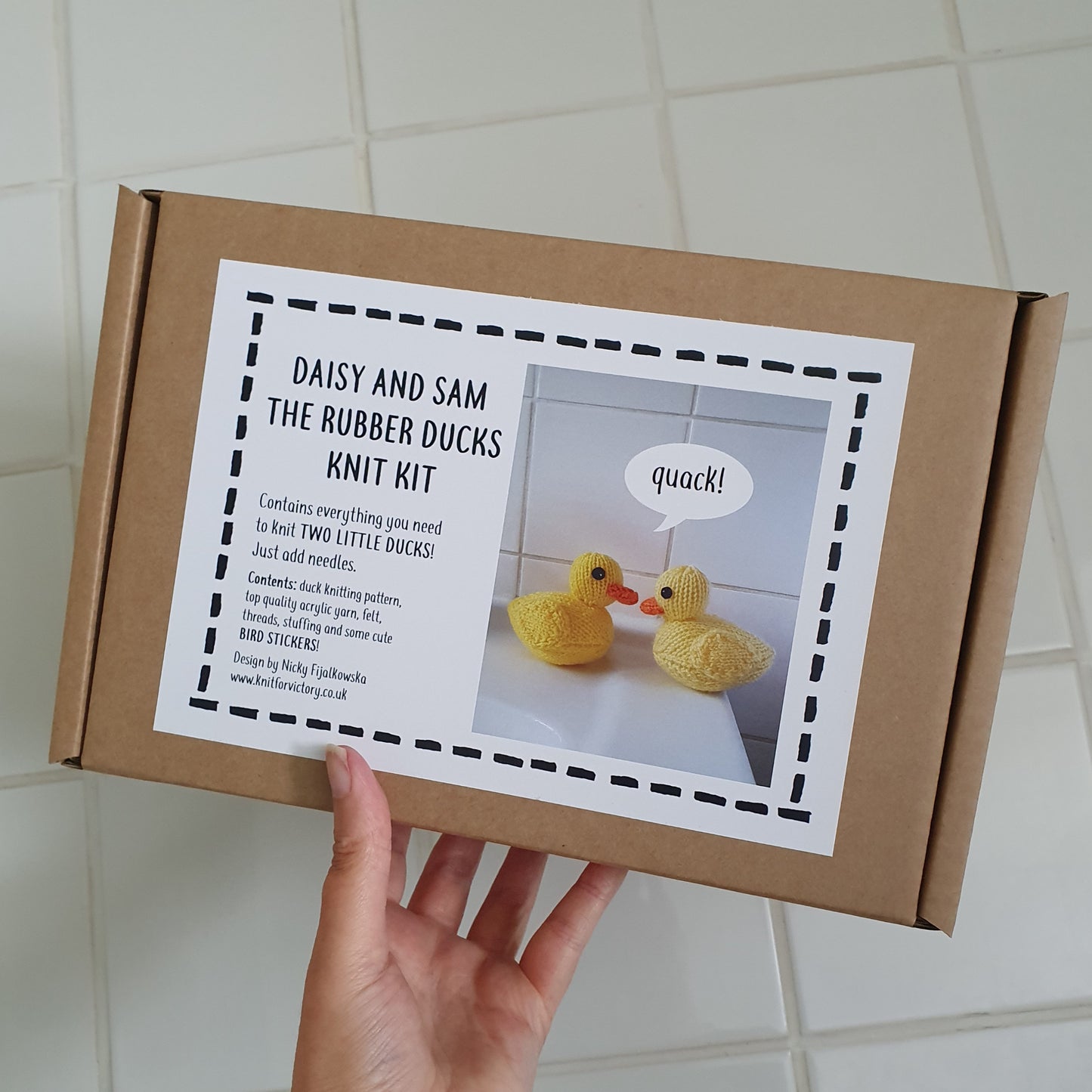A gift box containing a knitting kit for two yellow rubber ducks.