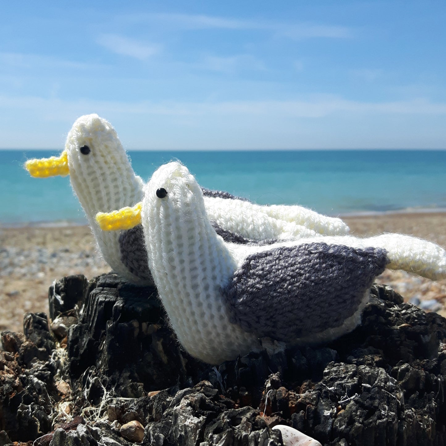 two knitted seagulls on the beach 