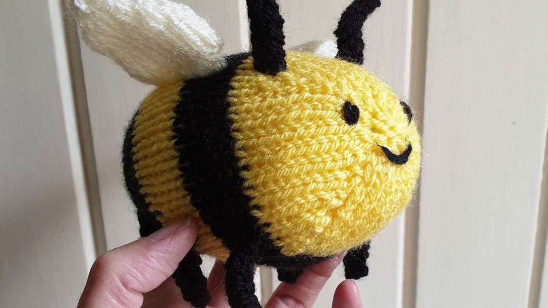 a knitted bee being held in the air