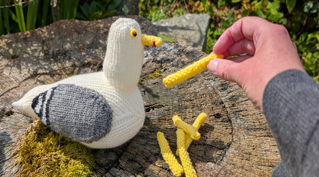 a knitted herring gull being fed knitted chips