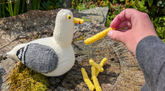 a knitted herring gull being fed knitted chips
