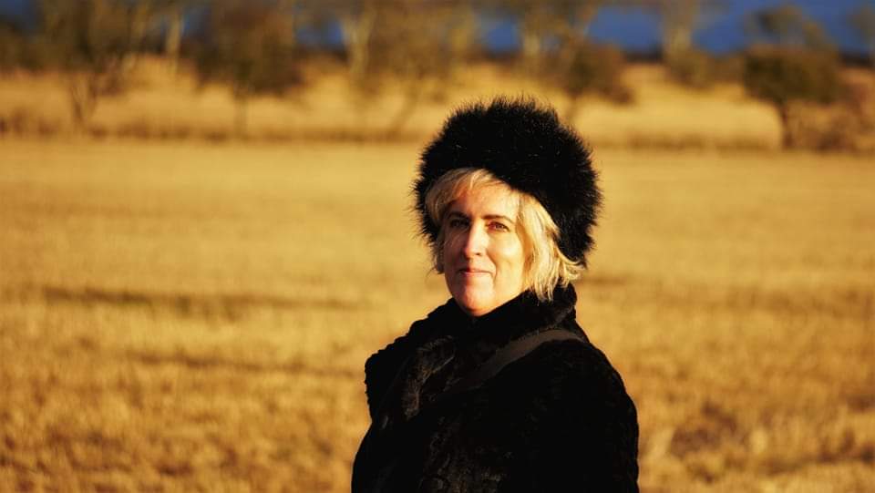 knitting deisgner Nicky Stewart standing in a golden corn field
