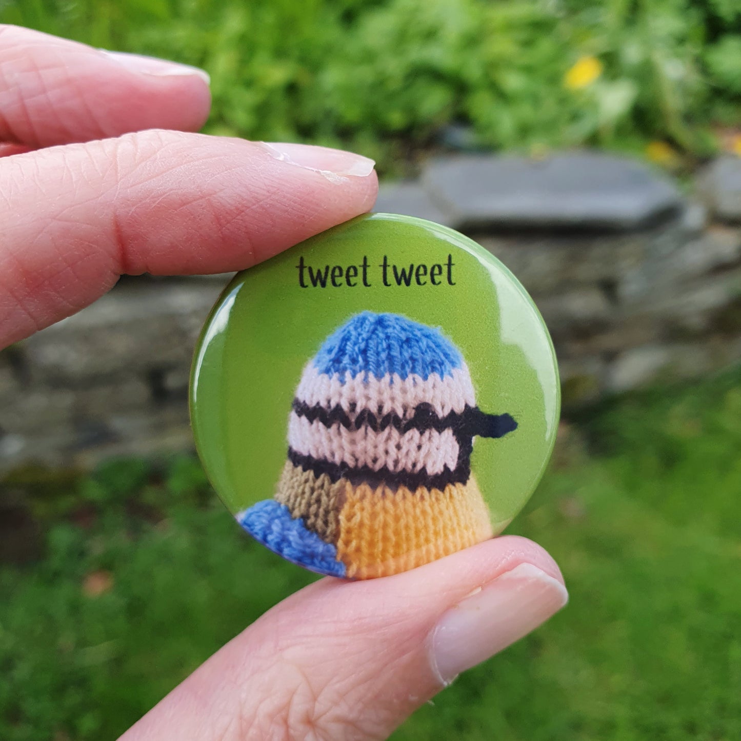 a button badge with a knitted blue tit on it